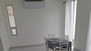 A dining area with a table and chairs, a window with curtains, and an air conditioning unit on the wall. - 3-bedroom house in charming Punta Cana with cool AC (Punta Cana)