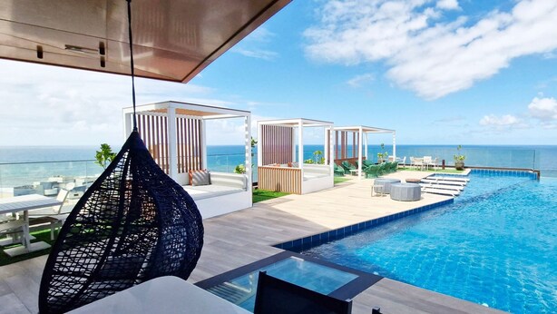 A rooftop infinity pool with a clear view of the ocean, outdoor seating, and a pergola structure. - COCAZ0109 - Condominio LIT 760 (Salvador)
