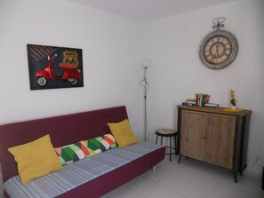 Een kamer met een bank, een kast, een klok en een lijst met een afbeelding.