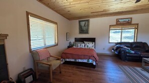 A bedroom with a bed, a chair, a couch, and a fireplace.