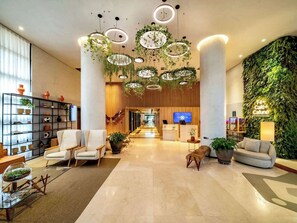 Eine moderne Lobby mit Empfangstresen, Sitzgelegenheiten und einer grünen Wand.