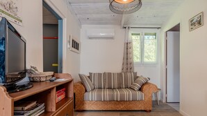 Uma sala de estar aconchegante com um sofá, uma escrivaninha de madeira com um computador e uma estante de livros.