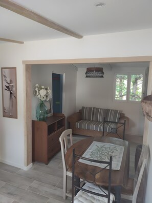 Un coin repas avec une table en bois, des chaises, un canapé et un vase de fleurs.