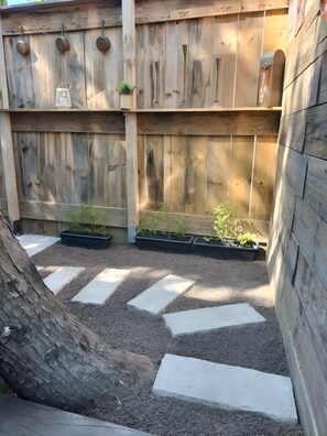 Une clÎture en bois agrémentée de jardiniÚres et de pas japonais.