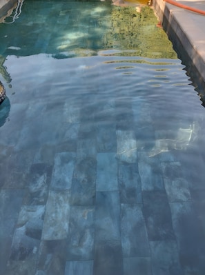 Una piscina con agua cristalina y piso de azulejos.