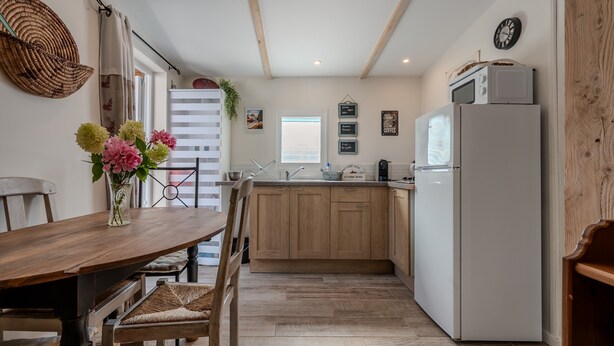 Uma cozinha com armários de madeira, uma geladeira branca e uma mesa de jantar com cadeiras.