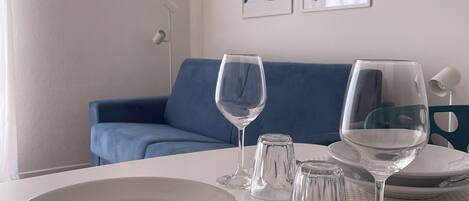 A dining area with a white table set for two, including plates, glasses, and cutlery.