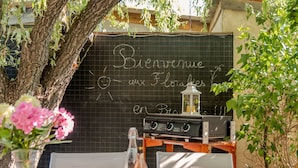 Un espacio de comedor al aire libre con una pizarra que muestra 'Bienvenue en Florale' y una estación de parrilla.