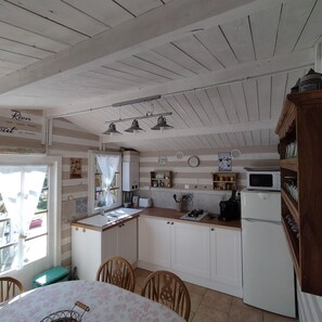 Une cuisine dotĂ©e de meubles en bois, dâun Ă©vier, dâun four Ă micro-ondes et dâun coin repas avec des chaises et une table.