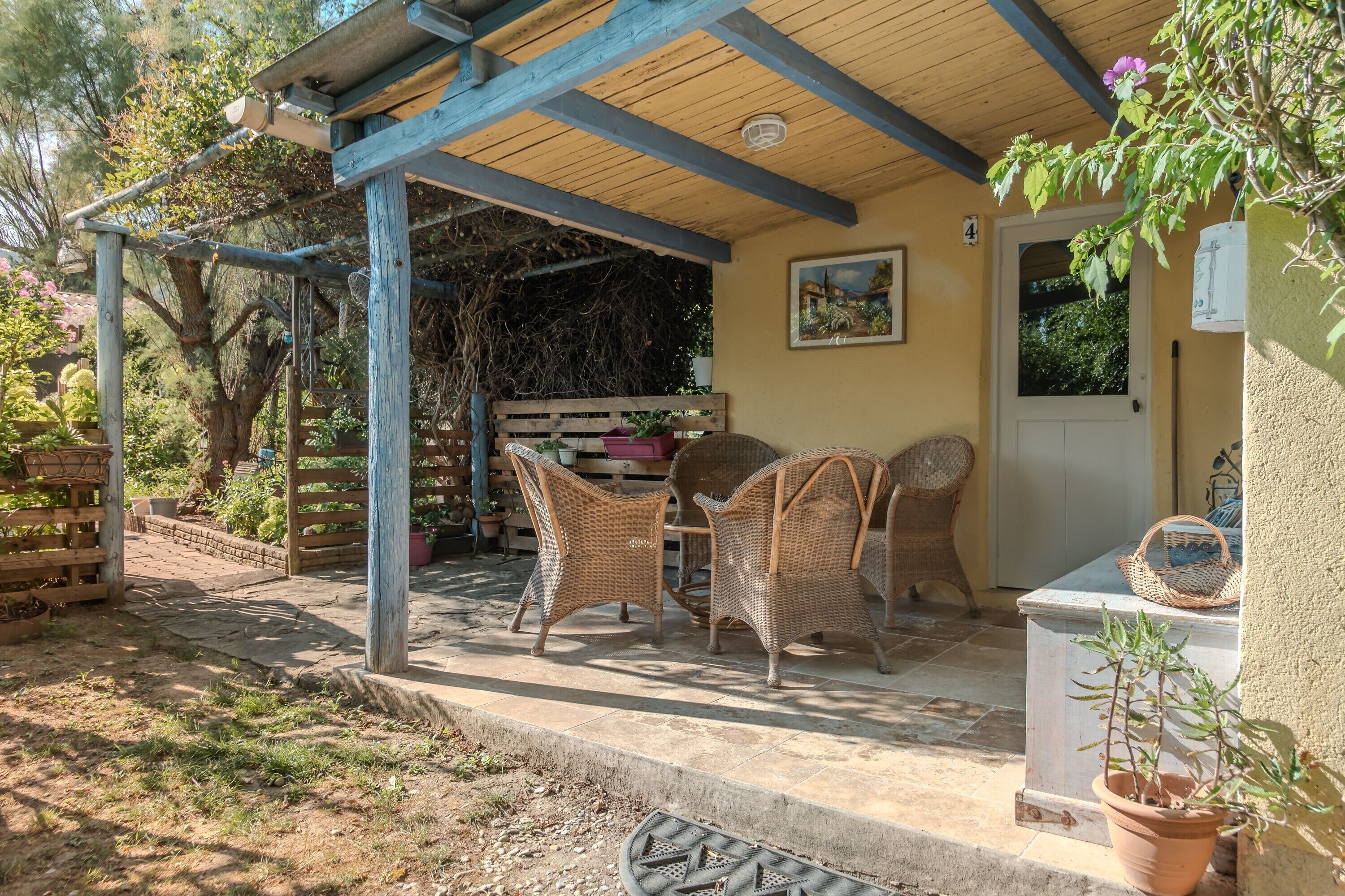 A covered patio area with wicker furniture, a door, and a potted plant.