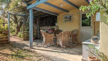 A covered patio area with wicker furniture, a door, and a potted plant.