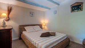 Un dormitorio acogedor con una cama de mimbre, ropa de cama a rayas y una mesita de noche con una lámpara.