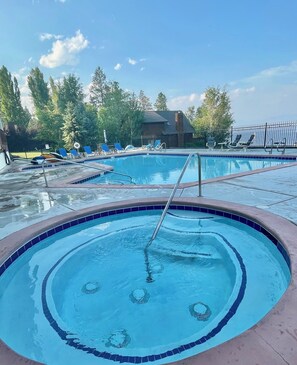 A swimming pool with a circular design, surrounded by lounge chairs and a fence.