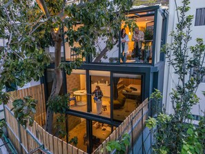 A modern two-story house with a balcony, a dining area, and a kitchen visible through large glass doors. - The 21 - Vortex by Homie (Ribeira Brava)