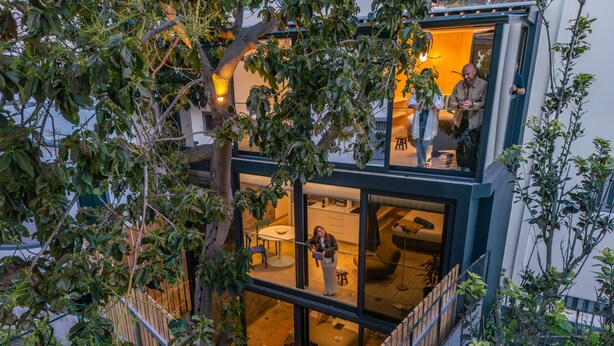 Ein modernes Haus mit einem Glasbalkon, einem Essbereich und einem Wohnzimmer.