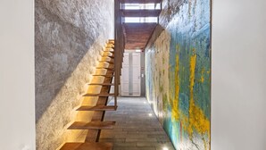 A narrow hallway with a wooden staircase leading to a door. - The 21 - Gaia by Homie (Ribeira Brava)
