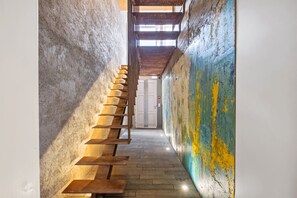 Ein schmaler Flur mit einer Holztreppe zu einer Tür.