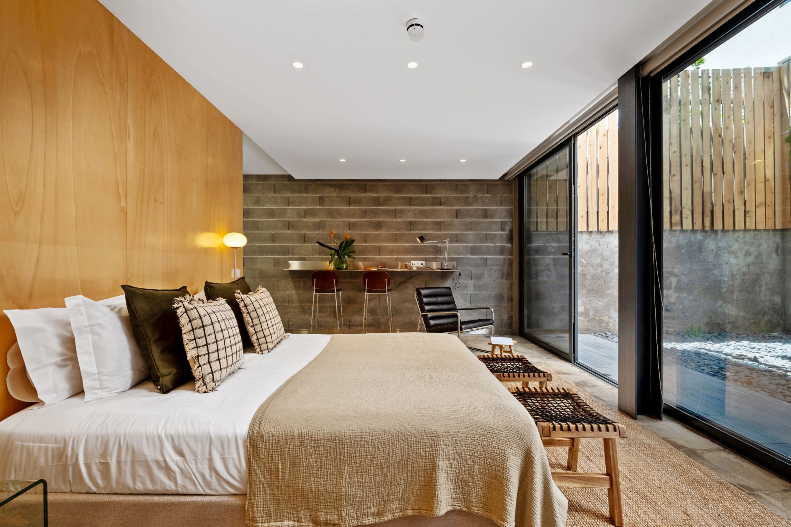 Habitación de hotel moderna con una cama grande, un escritorio y vistas a una terraza de madera.
