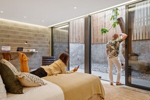 Ein modernes Interieur mit einem Bett, einem Schreibtisch und einer großen Glasdoor, die zu einem Außenbereich führt.