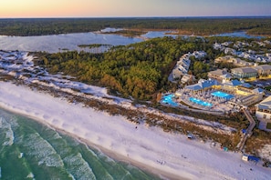 An aerial view of a coastal resort with a large pool area, beachfront, and dense forested area. - Watercolor Condo w/ Exclusive Pool Access (Santa Rosa Beach)