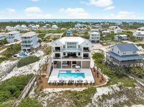 A beachfront property with a large pool, multiple balconies, and a view of the ocean. - Gulf Front Retreat with Pool and Peleton (North Cape San Blas)