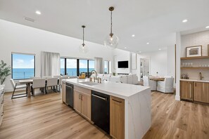 A modern kitchen with a central island, wooden flooring, and pendant lighting. - Gulf Front Retreat with Pool and Peleton (North Cape San Blas)