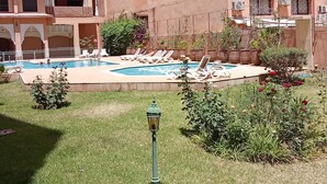 Un hôtel doté d’une piscine, de chaises longues et d’un jardin bien entretenu.