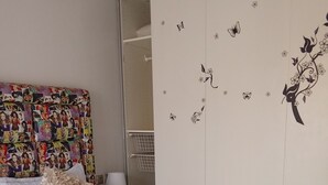 Une chambre d’hôtel comprenant un lit, une table de chevet, un miroir et un mur décoré de motifs floraux et de papillons.