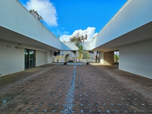 Ein Innenhof mit Backsteinfassade, weißen Wänden und blauem Himmel.