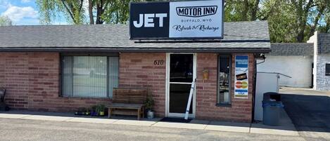 A Jet Motel sign, a brick building, a bench, and a door with a number 610.