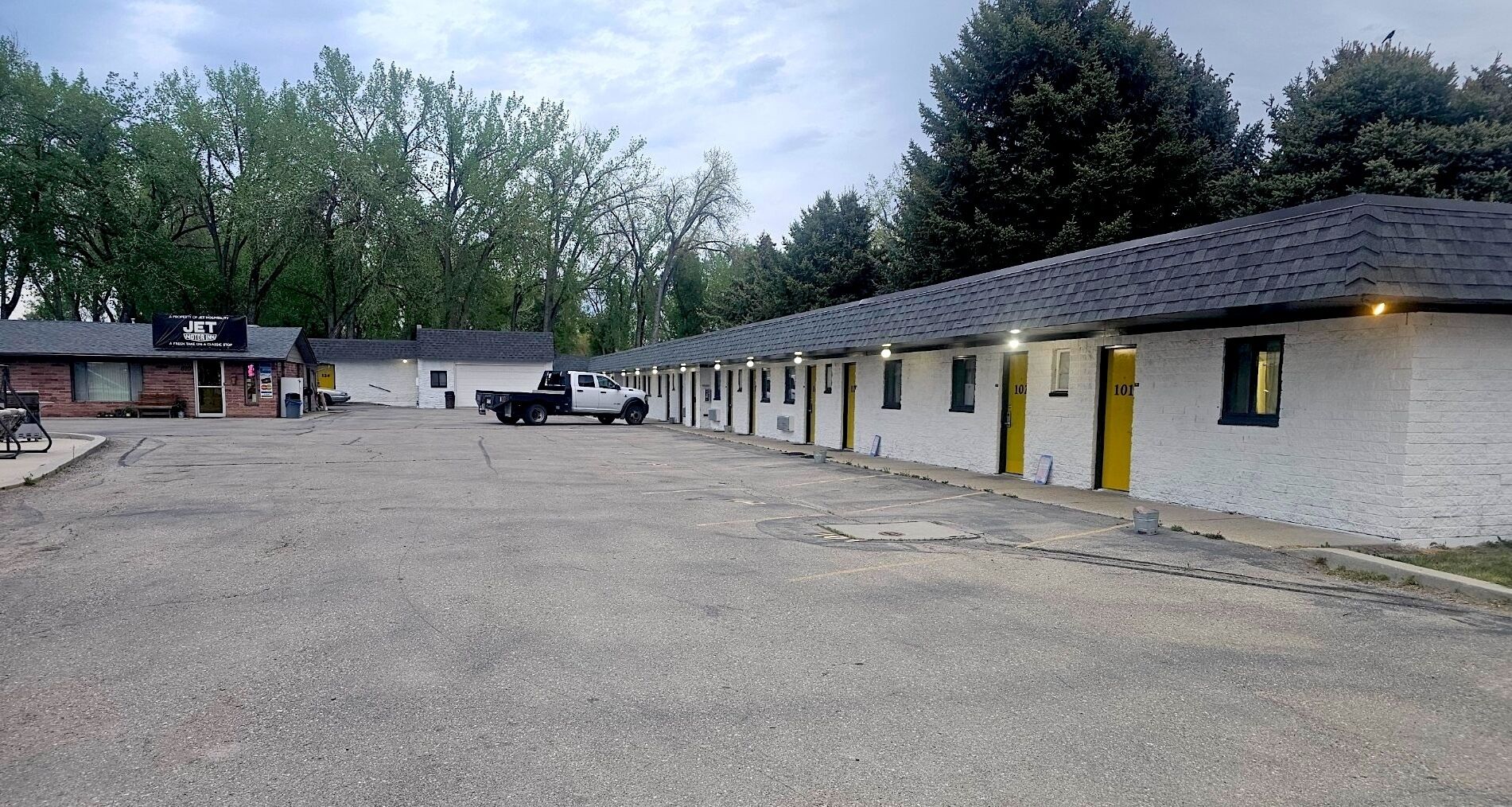 A motel with numbered rooms, a parking lot, and a truck parked in front.