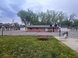 A motel with a brick building, a picnic table, and a bench in the foreground. - JET Motor Inn Buffalo (Buffalo)