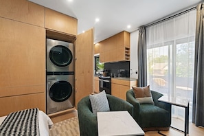 A compact living space with a kitchenette, a dining area, and a large window with curtains.