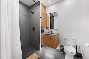 A modern bathroom with a shower, toilet, and vanity.