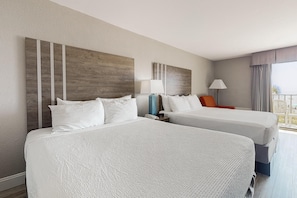 A hotel room with two beds, a nightstand, a lamp, and a view of the outdoors. - Oceanfront Balcony + Kitchen + Breakfast for 2 (Myrtle Beach)