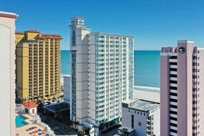 A high-rise hotel with multiple floors, a pool area, and a view of the beach. - Oceanfront Two Queen Room + Lazy River & Hot Tub (Myrtle Beach)