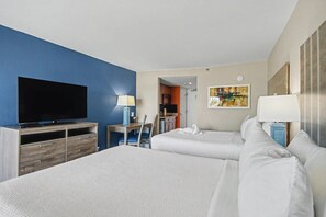 Habitación de hotel con una cama grande, televisión, escritorio con lámpara y un cuadro en la pared.