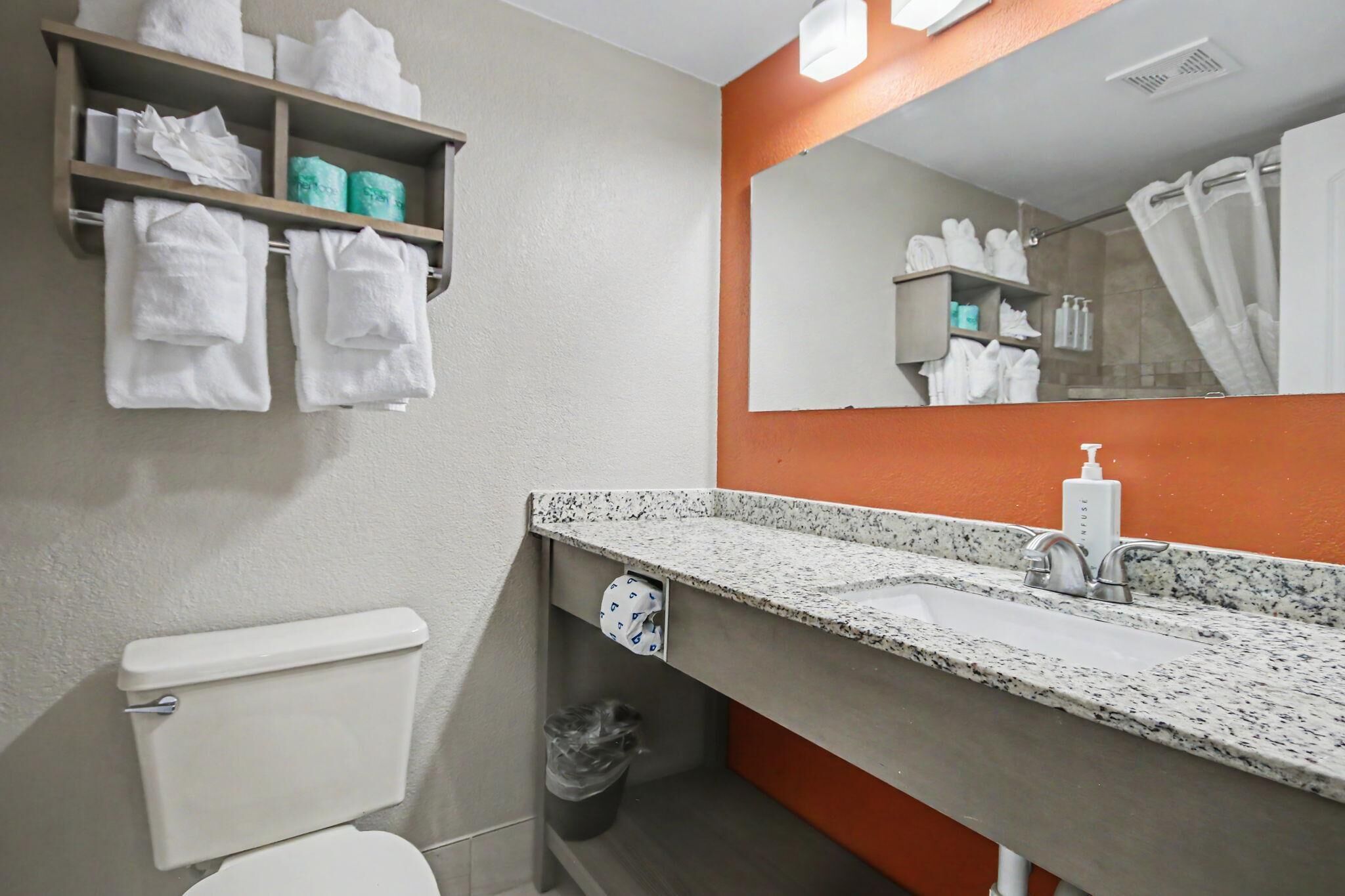 A bathroom with a toilet, sink, and towel storage.