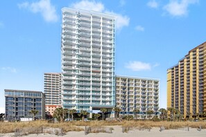 A multi-story hotel with balconies, a central atrium, and a beach view. - Oceanfront Two Queen Room + Lazy River & Hot Tub (Myrtle Beach)