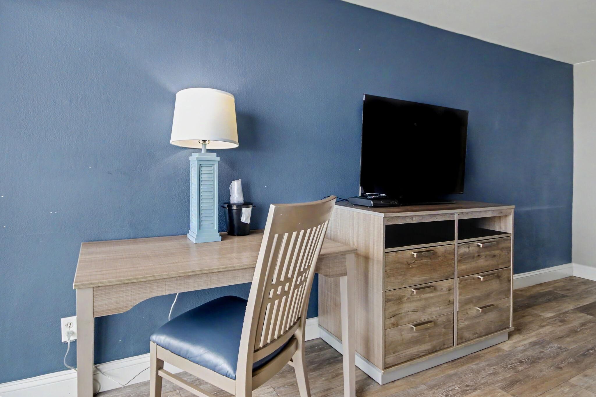 Une pièce comprenant un bureau, une chaise, un téléviseur, une lampe et un meuble de rangement.