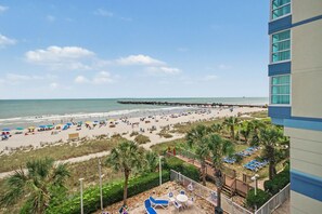 Uma praia com um píer, cadeiras de praia e guarda-sóis.
