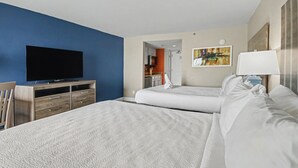 A hotel room with two beds, a TV, a desk, and a painting on the wall. - Oceanfront Two Queen Room + Lazy River & Hot Tub (Myrtle Beach)
