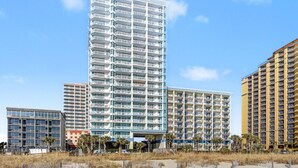 Un hotel de diverses plantes amb balcons, un atrium central i vista al mar.