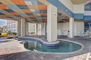 A pool area with tiled flooring, a curved pool, and a colorful ceiling.