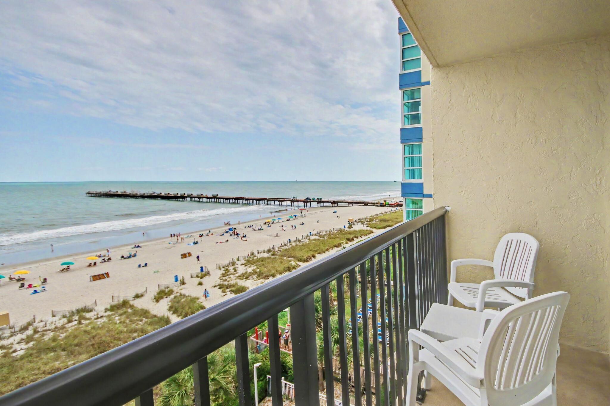 A balcony with a view of a beach and a pier.