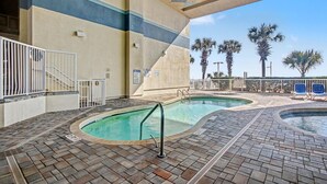 A pool area with two pools, a staircase, and palm trees in the background. - Oceanfront Two Queen Standard Room + Lazy River & Hot Tub (Myrtle Beach)