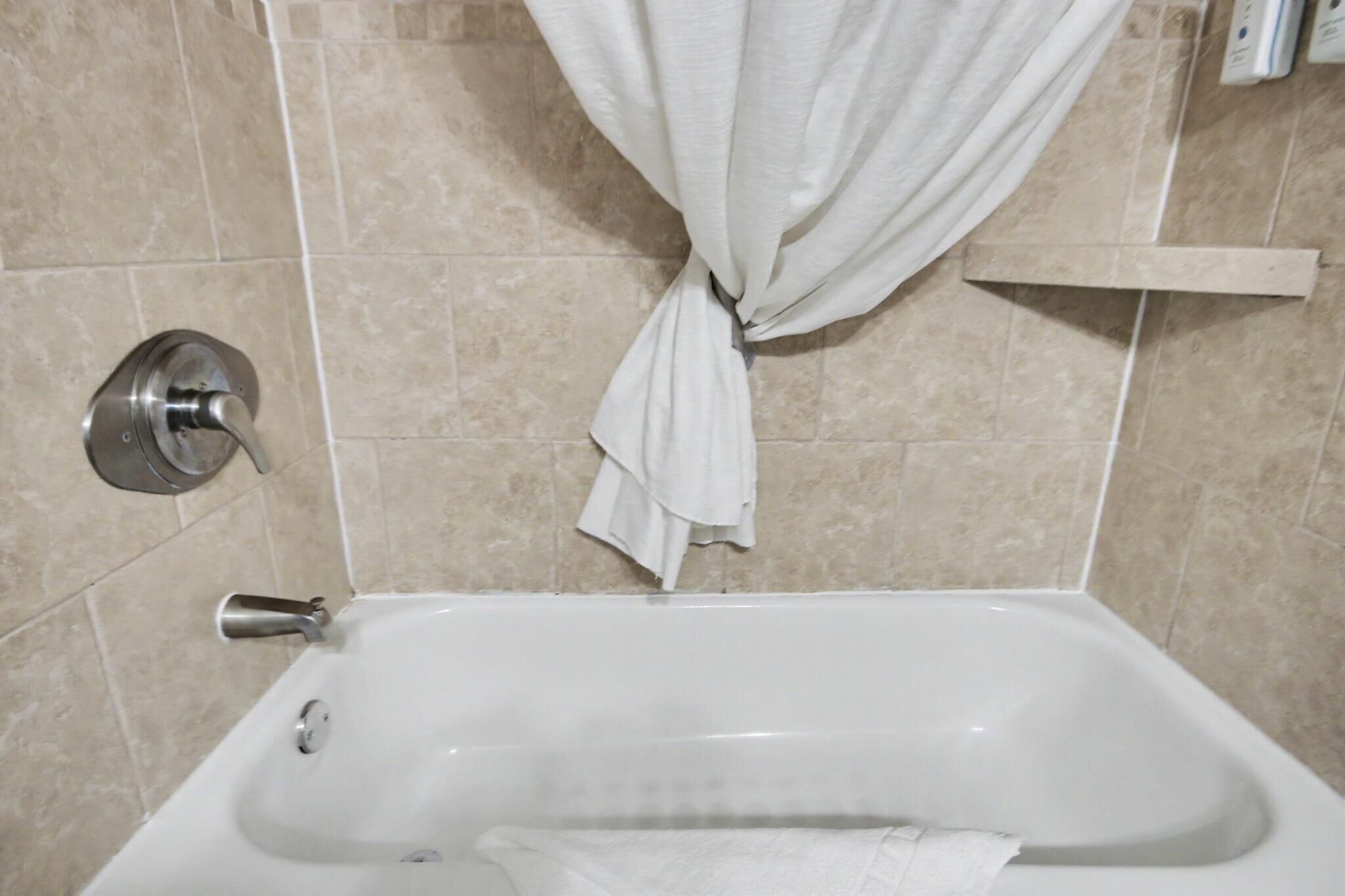 A bathroom with a bathtub, a shower curtain, and a towel rack.