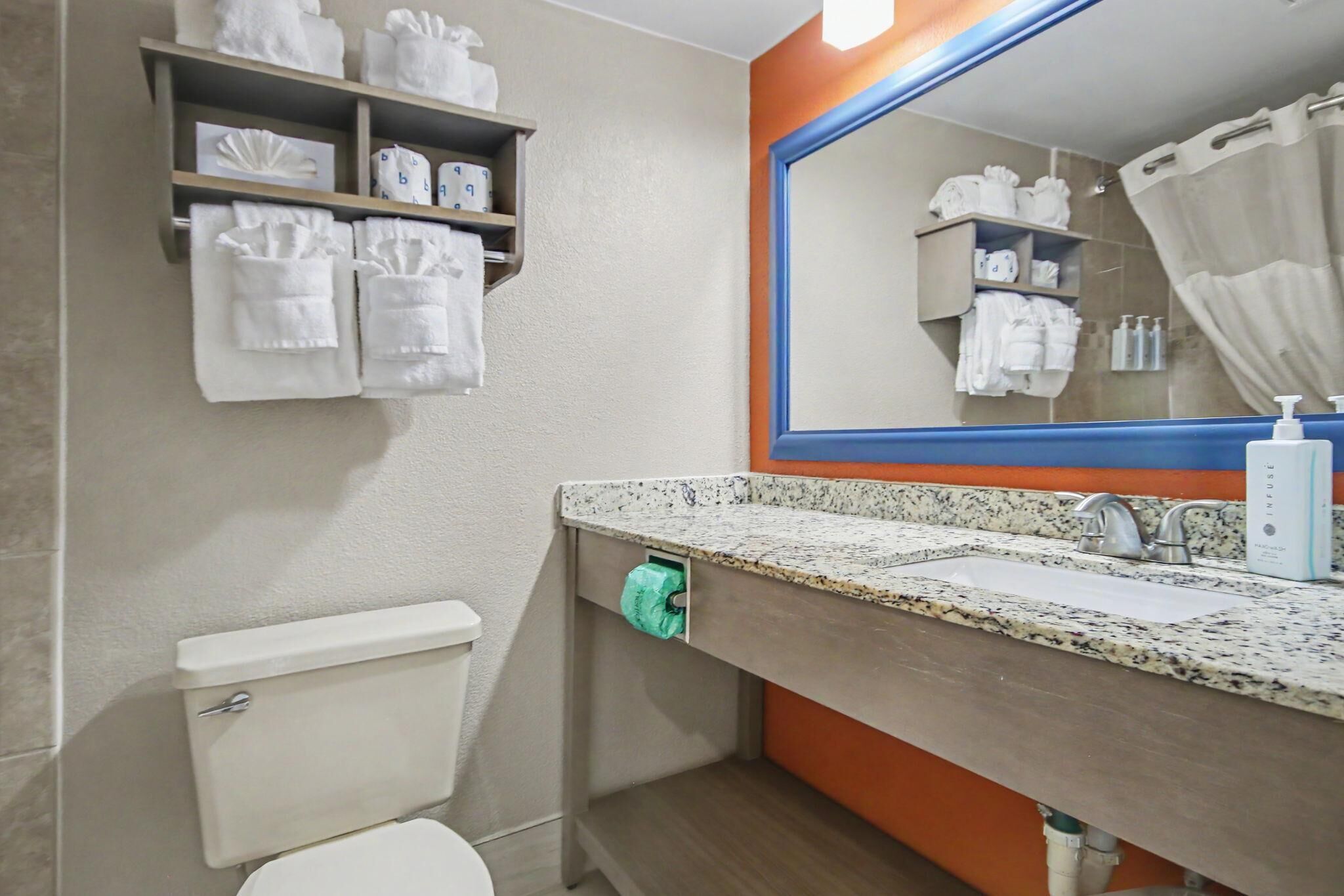 A bathroom with a toilet, sink, and shelves with towels.