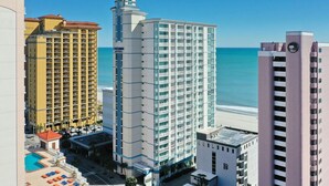 Ein Hochhaus-Hotel mit mehreren Etagen, einem Poolbereich und Blick auf den Strand.