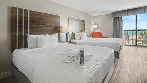 A hotel room with two beds, a desk with a lamp, and a view of the sea. - Oceanfront Two Queen Room + Lazy River & Hot Tub (Myrtle Beach)